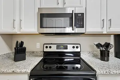 a kitchen with a stove and a microwave at Familiar 3 Quartos Perto da Disney! in Orlando
