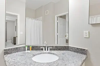 a bathroom with a sink and a large mirror at Familiar 3 Quartos Perto da Disney! in Orlando