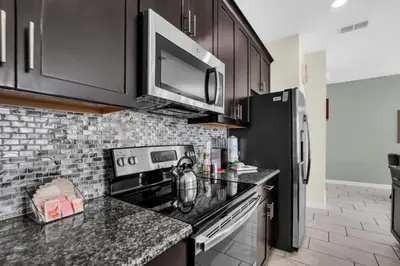a kitchen with black cabinets and a stove top oven at 4804Crusoe townhouse in Kissimmee