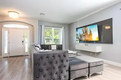 a living room with a couch and a tv on a wall at 6BD/4BA Windsor Hills | Sala de Jogos & Piscina in Orlando