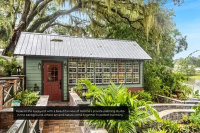 a small green building with a red door in a garden at Mills Cottage in Orlando