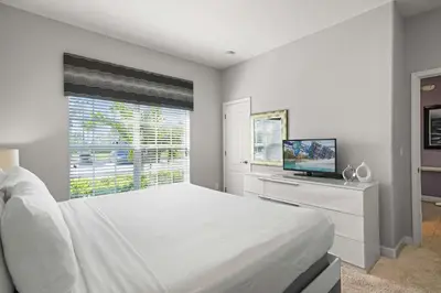 a white bedroom with a large bed and a television at 8929 Candy Palm Road in Kissimmee