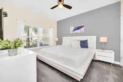 a white bedroom with a bed and a ceiling fan at 4829Lullaby townhouse in Kissimmee