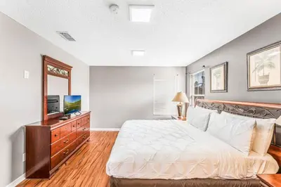 a bedroom with a white bed and a television at Emerald Island Large 8 Bed Home Golf Resort villa in Kissimmee