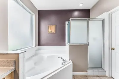 a bathroom with a tub and a window at Emerald Island Large 8 Bed Home Golf Resort villa in Kissimmee