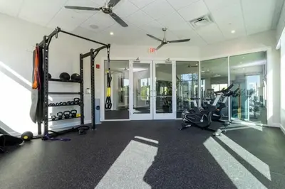a gym with cardio equipment in a room with windows at 4Q/3B Luxuosa e Moderna | Piscina Priv. in Kissimmee