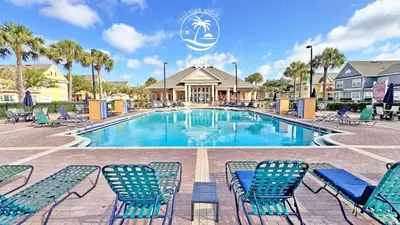 a swimming pool with blue chairs and palm trees at Deluxe 4 bedrooms Villa at Seven Dwrafs Resort - Close to Disney in Kissimmee