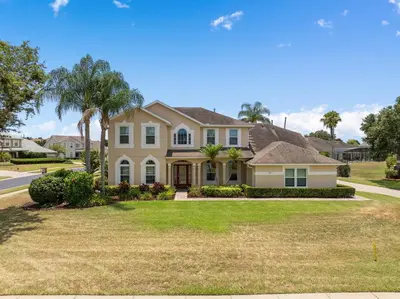 a house in a residential neighborhood with palm trees at Mickeys Sunrise - Phenomenal 7BR Themed Rooms Home Theater Swingset SplashPad Gas BBQ - 2 miles to Disney in Orlando