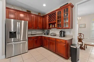 a kitchen with wooden cabinets and a stainless steel refrigerator at Mickeys Sunrise - Phenomenal 7BR Themed Rooms Home Theater Swingset SplashPad Gas BBQ - 2 miles to Disney in Orlando