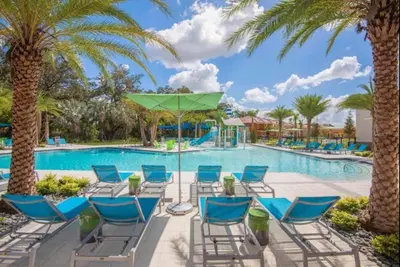 a pool at the resort with chairs and a green umbrella at 299- Fabulous 4 Bed Modern Decor Villa with Private Pool Overlooking Conservation and Water View in Kissimmee