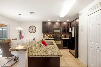 a kitchen with a counter and a kitchen with a clock at 299- Fabulous 4 Bed Modern Decor Villa with Private Pool Overlooking Conservation and Water View in Kissimmee