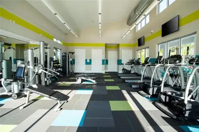a gym with several treadmills and machines in a room at 299- Fabulous 4 Bed Modern Decor Villa with Private Pool Overlooking Conservation and Water View in Kissimmee