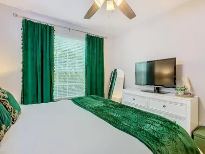 a bedroom with a bed with green curtains and a flat screen tv at Windsor Hills Cozy 3 BR Condo, Starwars, By Disney in Orlando