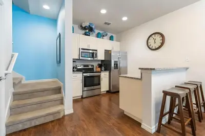 a kitchen with white cabinets and a counter with stools at Casa 3Q c/ Piscina de Resort e sala de jogos in Kissimmee