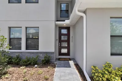a white house with a brown door at Spectacular! Townhome 9 Miles to Disney World! in Kissimmee
