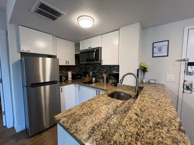 a kitchen with a stainless steel refrigerator and white cabinets at 22 -The heart of International Dr - Universal in Orlando