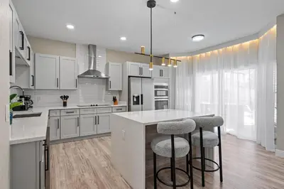 a kitchen with white cabinets and a island with bar stools at 6Q Windsor Hills, Piscina Privativa + Game Room in Orlando