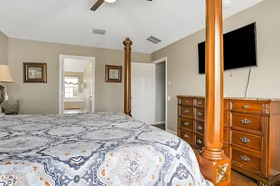 a bedroom with a bed and a dresser with a flat screen tv at Casa 6Q Familiar c/ Game Room Marvel e Piscina in Orlando