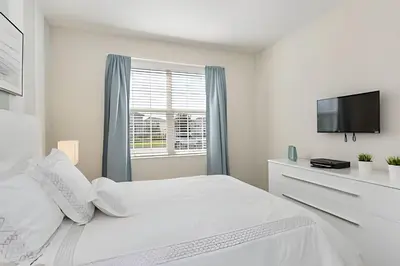 a white bedroom with a bed and a tv at Casa Resort com Piscina Aquecida e Pingue-Pongue in Kissimmee