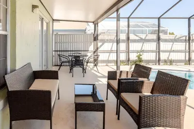 a balcony with wicker chairs and a table and a pool at 3Q/2B Vista para o Lago c/piscina | 10min->Disney in Kissimmee