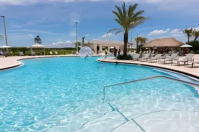 a large swimming pool with chairs and palm trees at Casa 5Q c/ Piscina – 10min da Disney + Resort in Kissimmee