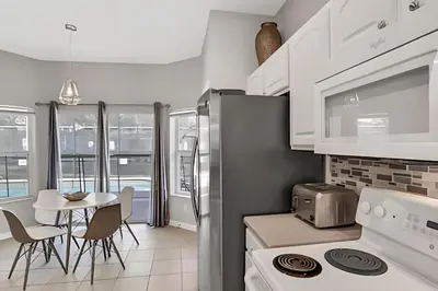 a kitchen with white appliances and a table with chairs at Villa 6Q Moderna c/ Piscina Priv. e Resort in Orlando