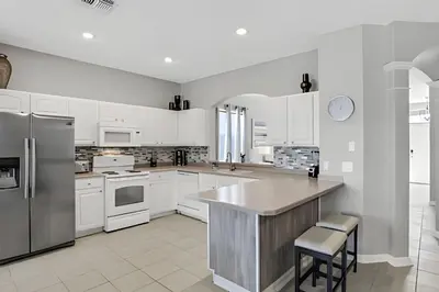 a kitchen with white cabinets and a large island at Villa 6Q Moderna c/ Piscina Priv. e Resort in Orlando