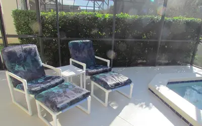 two chairs and a table next to a swimming pool at Grand Cumbrian - Four Bedroom Home in Kissimmee