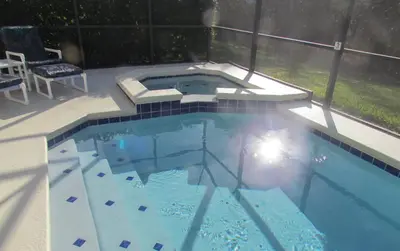a swimming pool with a table and chairs in it at Grand Cumbrian - Four Bedroom Home in Kissimmee