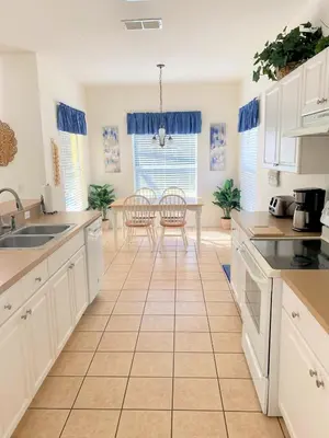 a kitchen with white cabinets and a table at Grand Cumbrian - Four Bedroom Home in Kissimmee