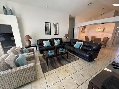 a living room with a black leather couch and a table at Daisy's Den - Five Bedroom Home in Kissimmee