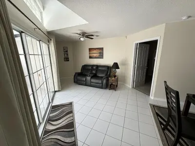 a living room with a black leather couch and a window at Villa Crayson in Kissimmee