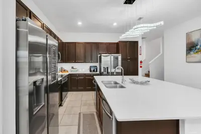 a kitchen with wooden cabinets and stainless steel appliances at Spacious Dreamscape 12rooms 11 bathrooms 25 people Wifi in Kissimmee