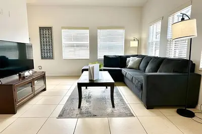 a living room with a black couch and a table at Casa aconchegante 4Q/3B Piscina Priv. in Kissimmee