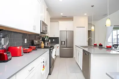 a large kitchen with white cabinets and red appliances at Villa 5 Quartos com Piscina no Storey Lake in Kissimmee