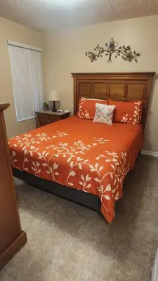 a bedroom with a bed with an orange comforter at Disney Area Condo at Laguna Bay Villas! in Kissimmee