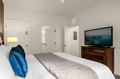a bedroom with a bed with a blue pillow and a flat screen tv at Casa 4Q c/ Piscina e Clubhouse — 10min da Disney in Kissimmee