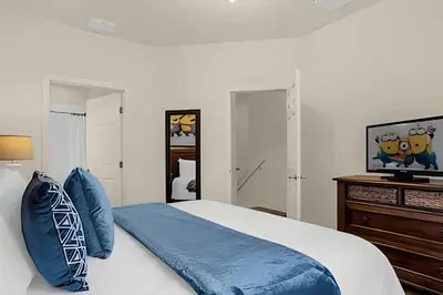 a bedroom with a bed with blue pillows and a television at Casa 4Q c/ Piscina e Clubhouse — 10min da Disney in Kissimmee