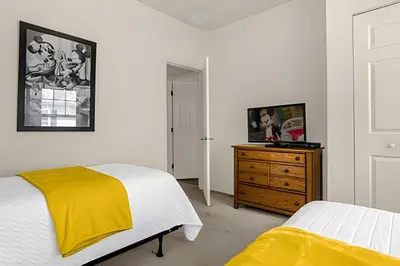 a bedroom with a bed and a dresser with a yellow blanket at Casa 4Q c/ Piscina e Clubhouse — 10min da Disney in Kissimmee