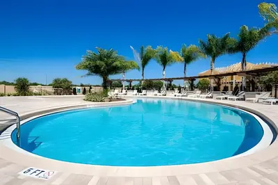 a swimming pool at a resort with palm trees at Casa 4Q c/ Piscina e Clubhouse — 10min da Disney in Kissimmee