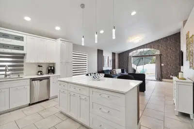 a kitchen with white cabinets and a living room at Fascinating Private Pool And Game-Room, Near Disney!! in Kissimmee