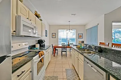 a kitchen with granite counter tops and a dining room at Splash, Play, with a Disney Stay in Orlando