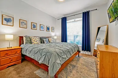 a bedroom with a bed and a dresser and a window at Splash, Play, with a Disney Stay in Orlando