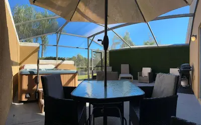 a patio with a table and chairs and an umbrella at 2BR Townhouse Near Disney in Kissimmee