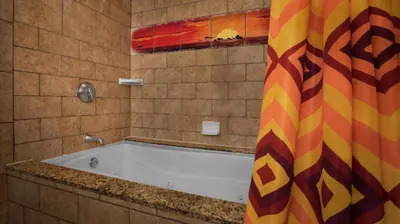 a bath tub in a bathroom with a colorful shower curtain at Disney's Animal Kingdom Villas - Jambo House in Orlando