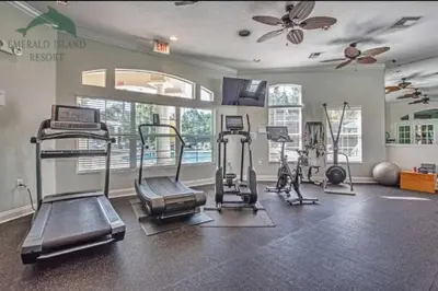 a gym with several treadmills and machines in a room at Scenic 3BR Family Retreat, Pool, Gym, 3mi to Disney in Kissimmee