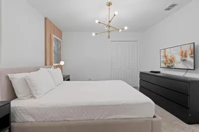 a white bedroom with a bed and a dresser at Brand New Home 9 Bedrooms5 Baths At Storey Lake in Kissimmee