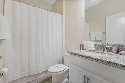 a white bathroom with a toilet and a sink at Amazing 5Bdrms At Storey Lake in Kissimmee
