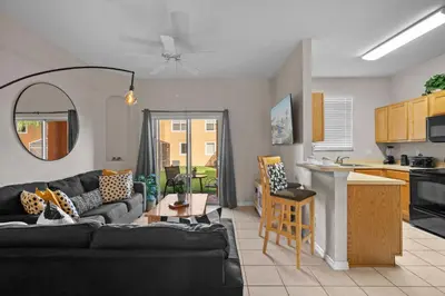 a living room with a black couch and a kitchen at Sweet 3 bedroom Townhome 2407 in Orlando