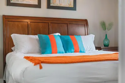 a bed with orange and blue pillows on it at Themed Villa, Great Location with proximity to Disney in Kissimmee